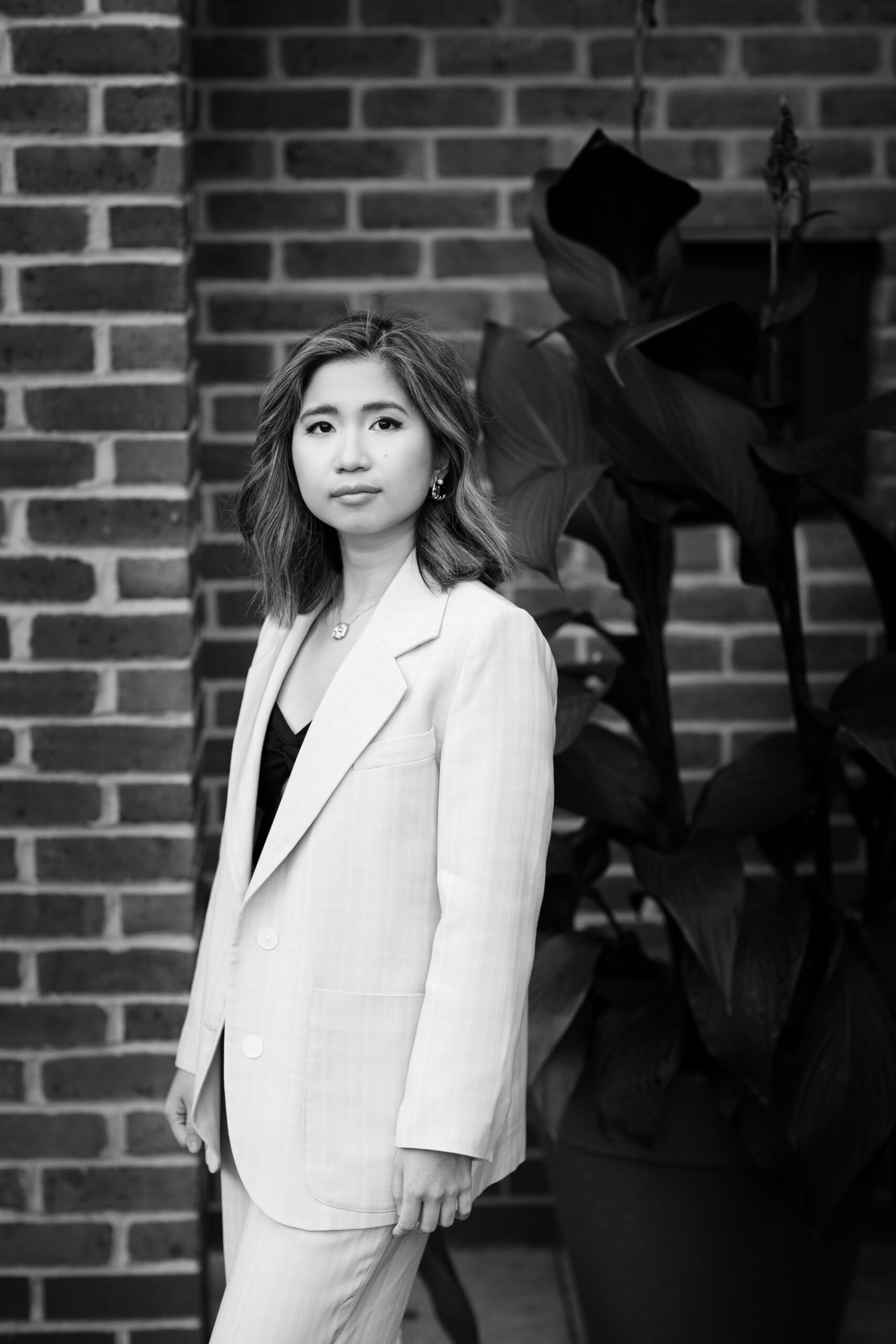 woman in suit against brick wall in black and white