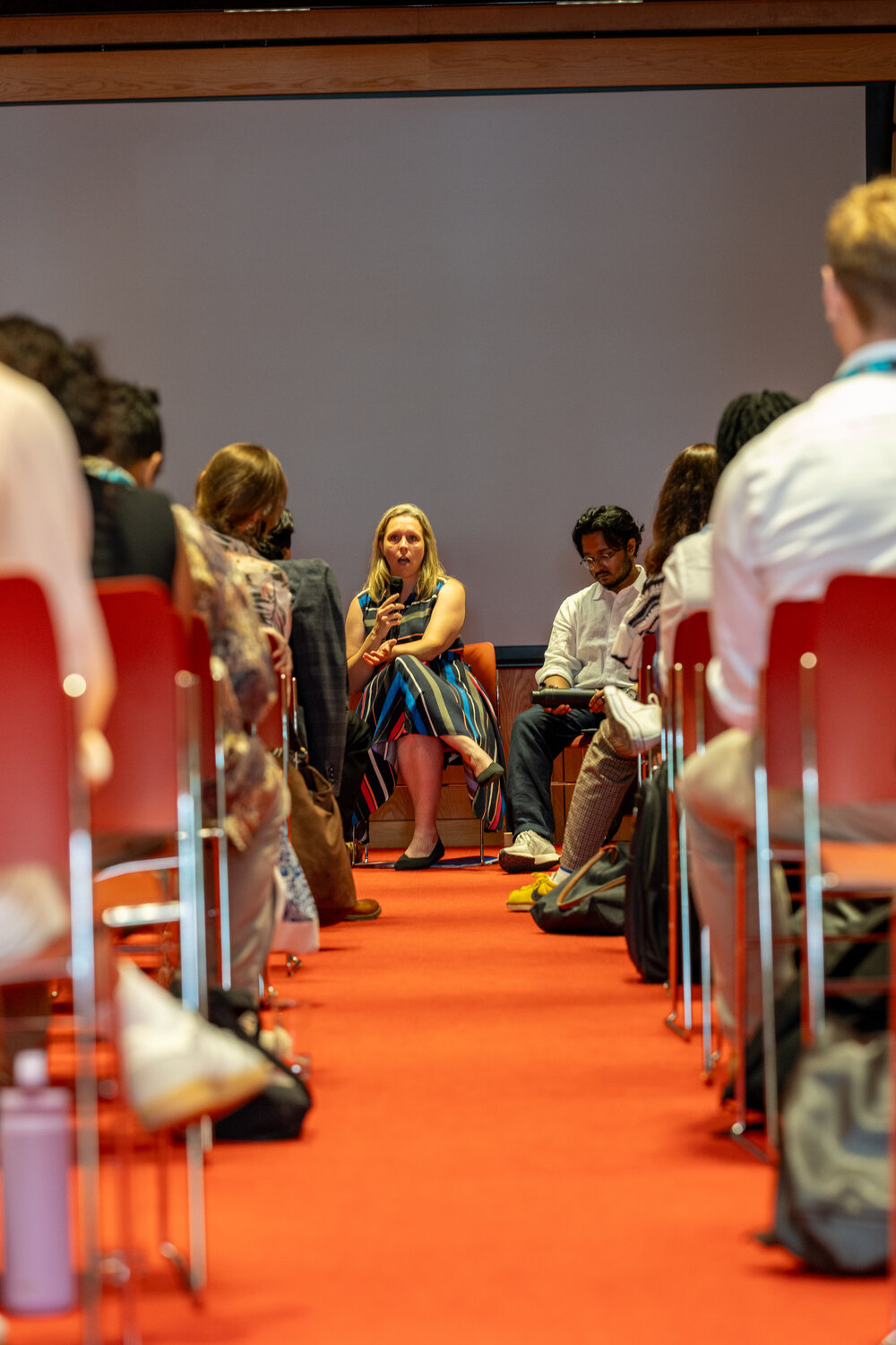 Room full of people with view of woman speaking
