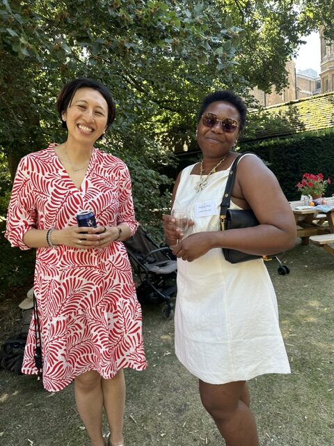 Two women smiling and holding drinks at garden party