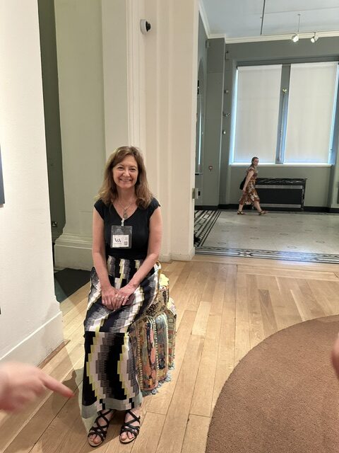 Woman sitting on stool in gallery