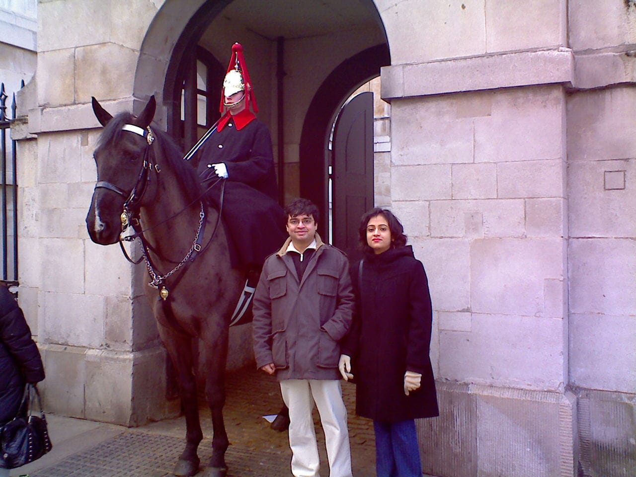 Man and woman standing in front of London guard on a horse