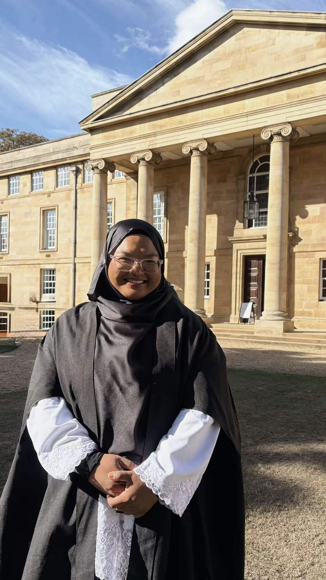 Woman in hijab smiling outside old building